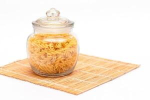 Uncooked Fusilli Pasta in Glass Jar on White Background. Raw and Dry Macaroni. Unhealthy and Fat Food. Italian Culture photo