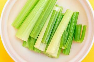 Fresh Chopped Celery Sticks with Water Drops in White Bowl Top View. Vegan and Vegetarian Culture. Raw Food. Healthy Diet with Negative Calorie Content photo