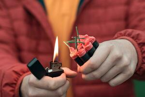 Man in Red Jacked Lighting Up Several Firecrackers in his Hand Using Gasoline Lighter. Guy Getting Ready for New Year Fun with Fireworks or Pyrotechnic Products photo