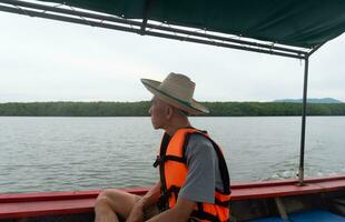 An adult Asian traveler sitting on long tail boat. Sustainability travel concept. photo