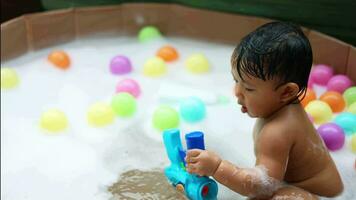 crianças jogando dentro a piscina. bebê jogando multicolorido bola dentro a pequeno piscina. video