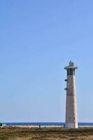 un faro en el playa con un azul cielo foto