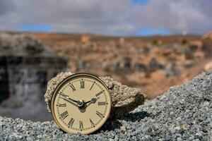 a clock on a rock in front of a desert photo