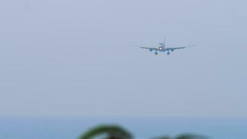 Jet passenger plane with an unrecognizable landing approach. Airliner flies over the sea, long shot, front view video