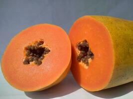 The papaya fruits on a wooden table and a rustic fabric at the background photo