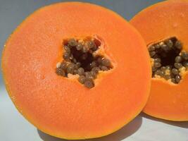 The papaya fruits on a wooden table and a rustic fabric at the background photo