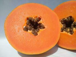 The papaya fruits on a wooden table and a rustic fabric at the background photo