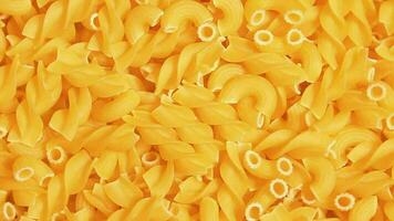 ongekookt fusilli en chifferi rigati pasta top visie. dik en ongezond voedsel. klassiek droog macaroni, langzaam roterend achtergrond. rauw verschillend macaroni pasta structuur draaien links video