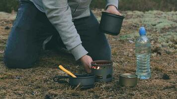 Man in a Hike is Cooking and Pouring Water from the Bottle into the Pot. Traveler in a Forest is Heating Food Using Small Cook Set video