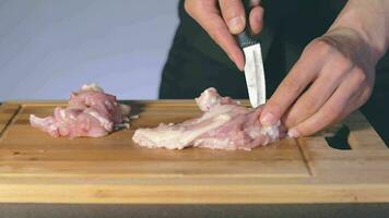 chef dans noir uniforme est Coupe poulet filet. Boucher est en train de préparer nourriture Ingrédients pour cuisine lent mouvement. statique coup video