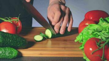 hombre rebanar Pepino mientras mujer roba otro vegetales desde el mesa. fuerte impaciencia para comiendo. familia gracioso Cocinando concepto. de cerca disparo, estático ver video