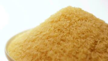 droog ongekookt voorgekookt rijst- hoop roterend tegen wit achtergrond. een stapel van rauw lang graan rijst. Aziatisch keuken en cultuur. gezond aan het eten ingrediënten. eetpatroon voedsel video