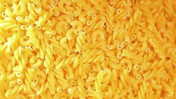 ongekookt fusilli en chifferi rigati pasta top visie. dik en ongezond voedsel. klassiek droog macaroni, roterend achtergrond. rauw verschillend macaroni pasta structuur draaien links video