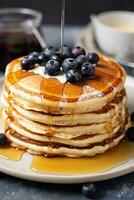 AI generated A stack of fluffy pancakes topped with blueberries and a drizzle of maple syrup photo