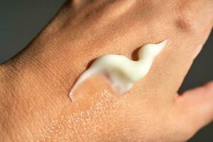 A smear of white moisturizer or sunscreen on a woman's hand. photo