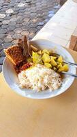 a plate of rice, tamarind vegetables, chili sauce, tempeh and salted fish on the table, suitable for advertising typical food photo