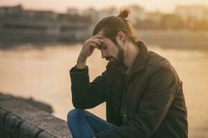 Depressed modern businessman sitting by the river.Toned image photo