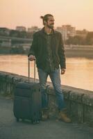 Handsome businessman with suitcase standing by the river.Toned image photo