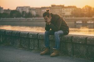 Depressed modern businessman sitting by the river.Toned image photo