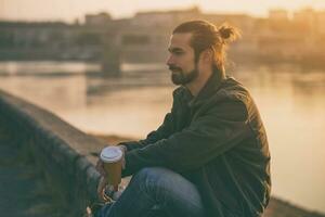 hermoso moderno empresario disfruta Bebiendo café y descansando por el río.tonado imagen. foto