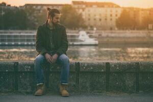 Depressed modern businessman sitting by the river.Toned image. photo