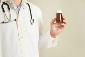 Image of male doctor holding bottle of pills. photo