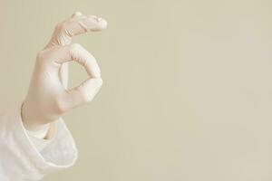 Image of close up hand in protective glove of doctor showing ok sign. photo