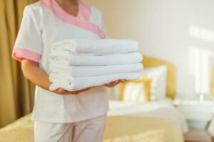 Close up image of hotel maid holding fresh and clean towels. photo