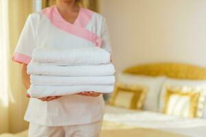 Close up image of hotel maid holding fresh and clean towels. photo