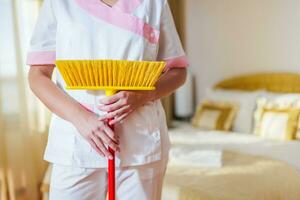 Close up image of hotel maid holding broom. photo