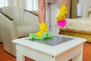 Close up image of hotel maid cleaning table in a room. photo