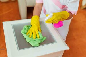 Close up image of hotel maid cleaning table in a room. photo