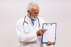 Portrait of senior doctor showing with pen clipboard on gray background. photo