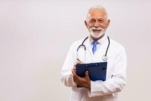 Portrait of  senior doctor writing notes  on  gray background. photo