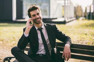 Elegant businessman using phone while sitting outdoor.Toned image photo