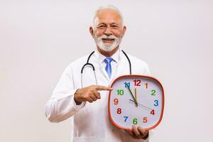 Portrait of senior doctor holding clock on gray background. photo