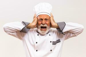 Portrait of  senior chef in panic on gray background. photo