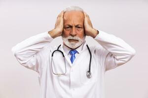 Image of tired senior doctor having headache on gray background. photo