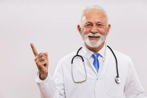 Portrait of senior doctor pointing on gray background. photo