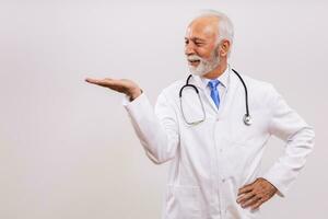 Portrait of senior doctor gesturing on gray background. photo