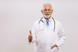 Portrait of senior doctor showing thumb up on gray background. photo