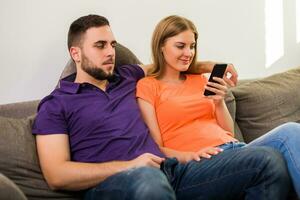 Wife using phone while her curious and jealous husband watching what does she typing. photo
