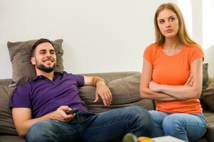 Angry wife and husband are having conflict because husband is watching tv too much. photo