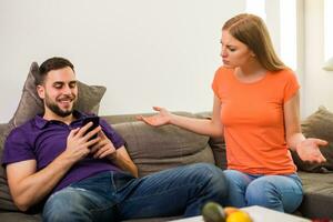Angry wife and husband are having conflict because husband is using phone too much. photo