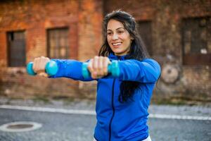 Beautiful woman exercising outdoor with weights outdoor. photo