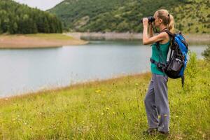 Woman hiker using binoculars while spending time in the beautiful nature. photo