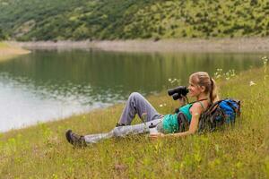 Woman hiker using binoculars while spending time in the beautiful nature. photo