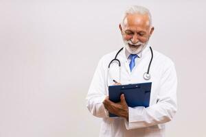 Portrait of  senior doctor writing notes  on  gray background. photo