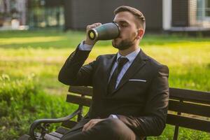 Elegant businessman enjoys drinking coffee while sitting outdoor.Toned image. photo