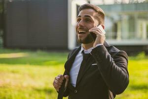 Elegant businessman using phone while standing outdoor.Toned image. photo